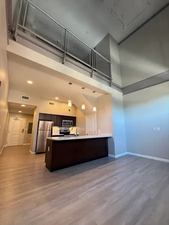 a view of a big room with wooden floor and kitchen