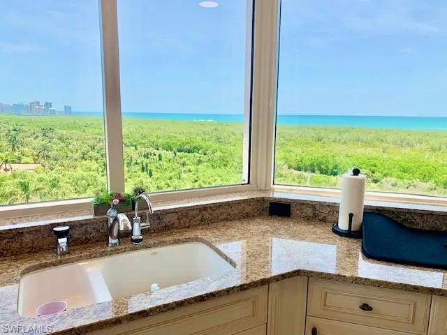 a bathroom with a granite countertop sink and a large mirror next to a window