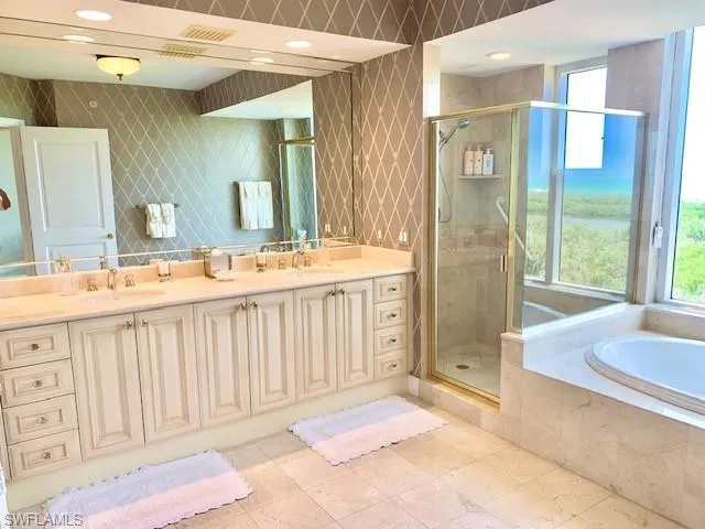 a spacious bathroom with a double vanity sink a mirror and a shower