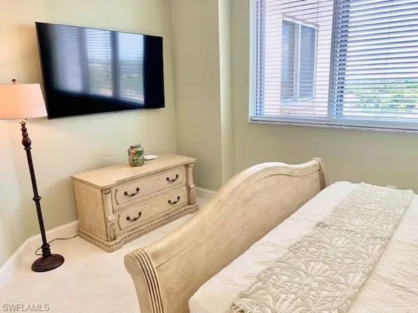 a bedroom with a bed and a flat tv screen on dresser
