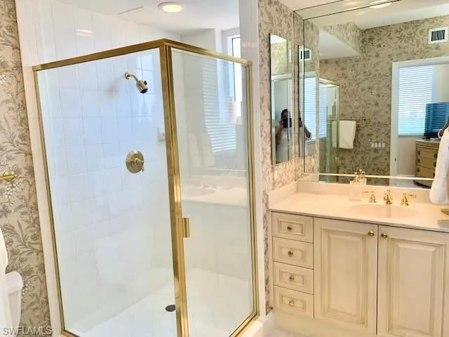 a bathroom with a granite countertop shower sink vanity and mirror