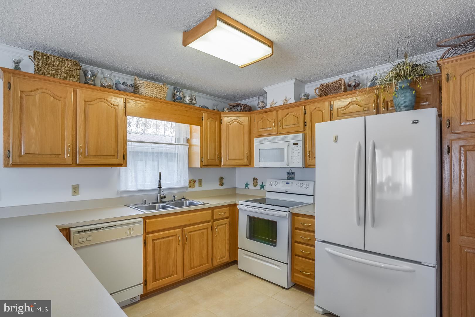 13702 Sailing Road Ocean City, MD 21842 - Photo 11 of 32 a kitchen with a sink a refrigerator and cabinets