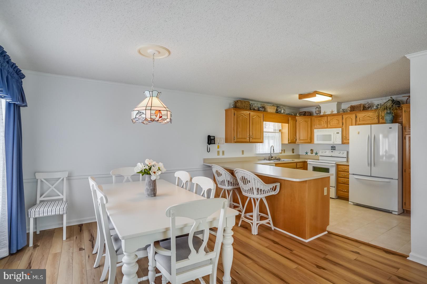 13702 Sailing Road Ocean City, MD 21842 - Photo 5 of 32 a kitchen with a table chairs refrigerator and microwave