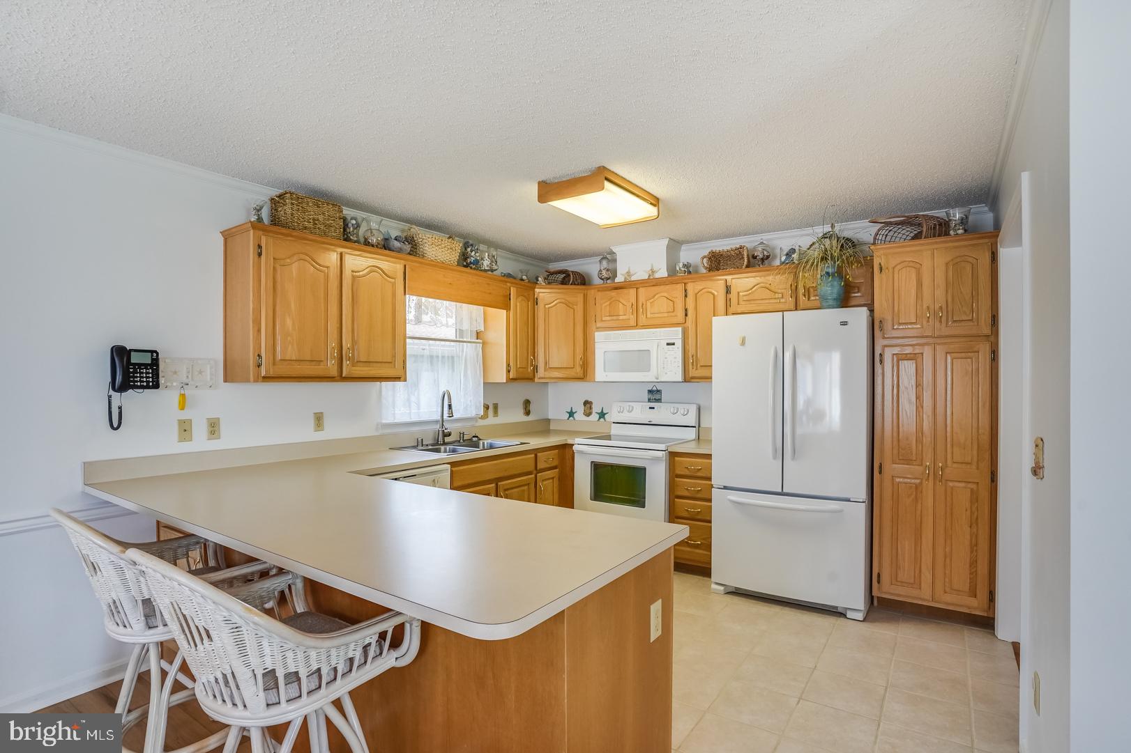 13702 Sailing Road Ocean City, MD 21842 - Photo 8 of 32 a kitchen that has a refrigerator a stove a sink and a dining table