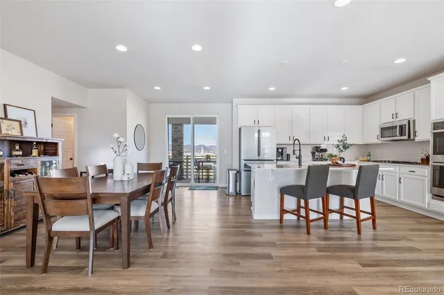 a kitchen with stainless steel appliances granite countertop white cabinets a sink a stove a refrigerator and island with wooden floor