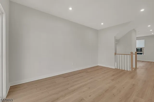 a view of kitchen with stainless steel appliances refrigerator oven and white cabinets with wooden floor
