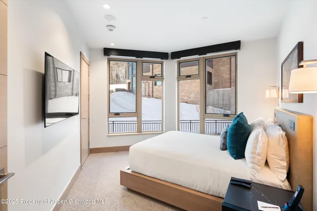 a bedroom with a bed and large windows