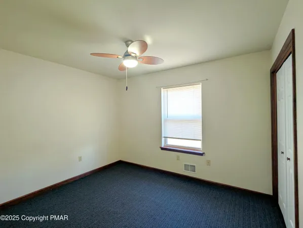 an empty room with a window and a fan