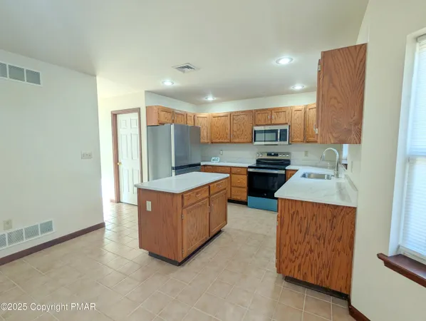 a large kitchen with stainless steel appliances kitchen island granite countertop a refrigerator and a stove top oven