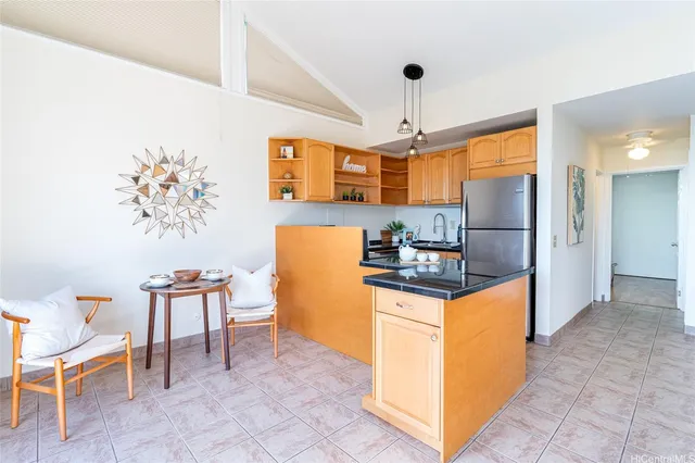 a kitchen with granite countertop a refrigerator a stove top oven and a dining table