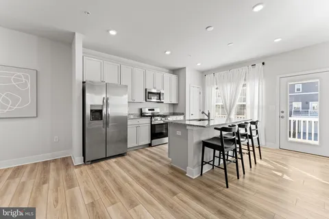 a kitchen with stainless steel appliances a refrigerator a stove top oven and a dining table with wooden floor