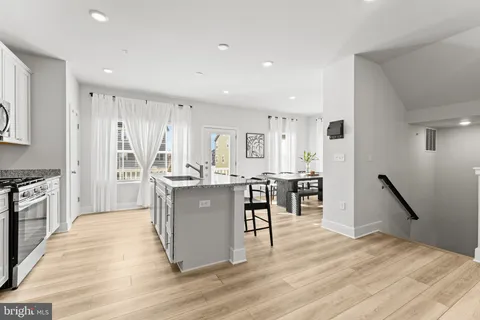 a kitchen with stainless steel appliances granite countertop a refrigerator oven a sink dishwasher and white cabinets with wooden floor