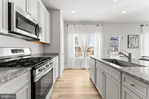 a kitchen with stainless steel appliances granite countertop a stove a sink and a microwave