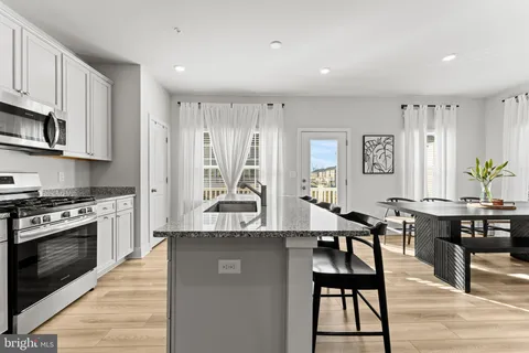 a large kitchen with granite countertop a stove a sink a table and chairs