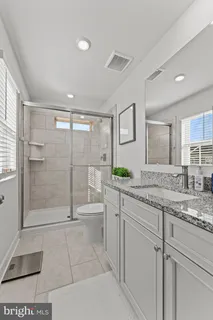 a bathroom with a granite countertop sink a toilet and shower