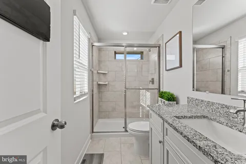 a bathroom with a granite countertop sink mirror vanity and toilet