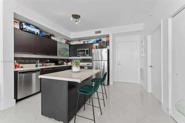 a living room with stainless steel appliances furniture and a flat screen tv