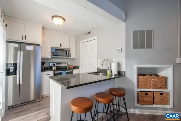 a kitchen with stainless steel appliances granite countertop a sink a stove and a wooden floor