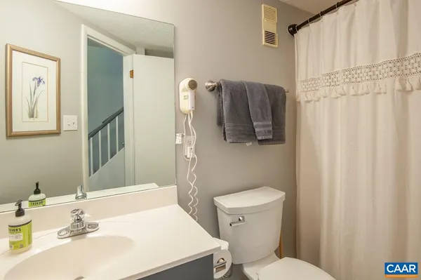 a view of a hallway with bathroom and wooden floor