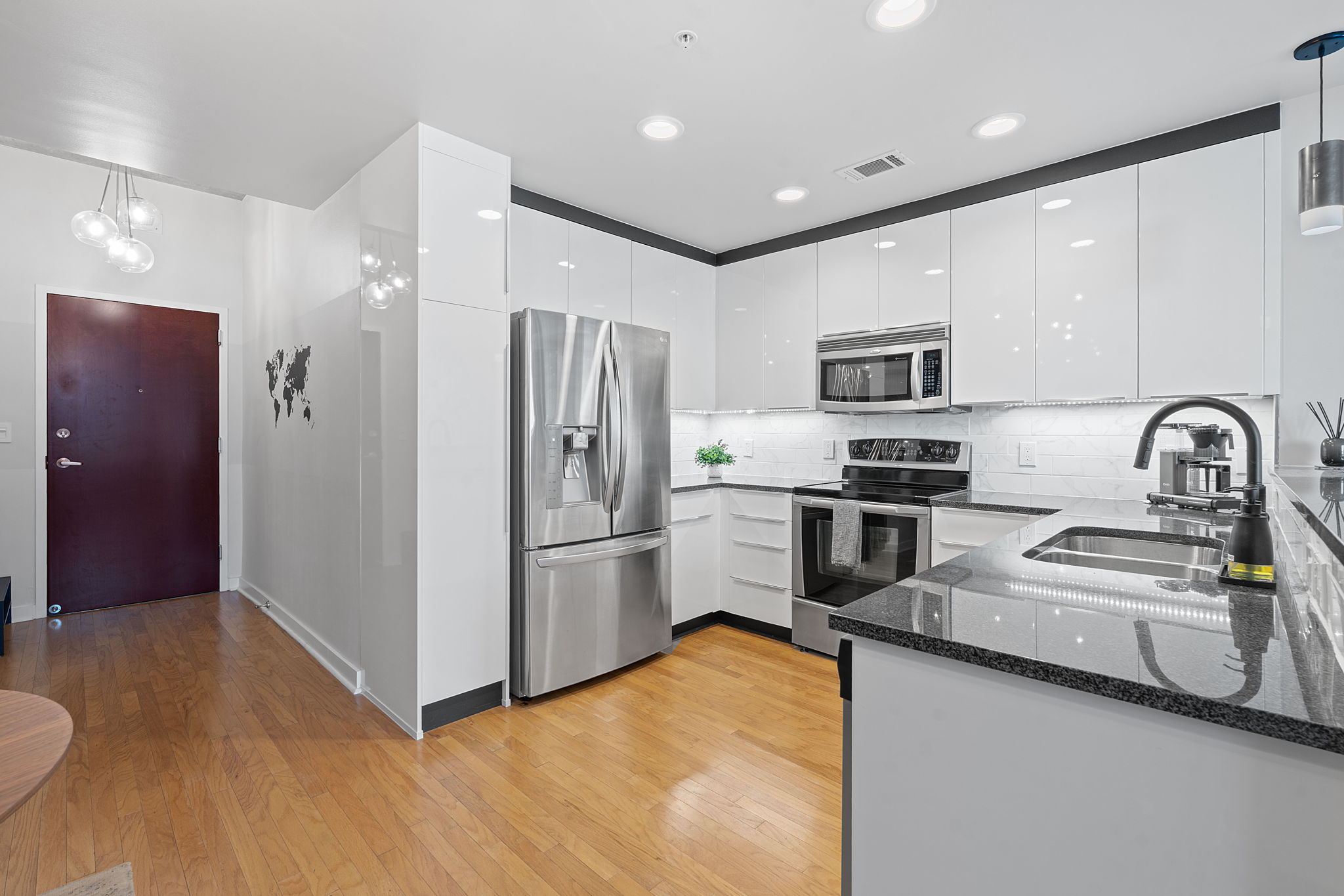 360 Nueces Street, Unit 1007 Austin, TX 78701 - Photo 8 of 40 Kitchen with decorative light fixtures, dark stone countertops, stainless steel appliances, white cabinetry, and tasteful backsplash