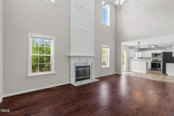 an empty room with wooden floor a fireplace and windows