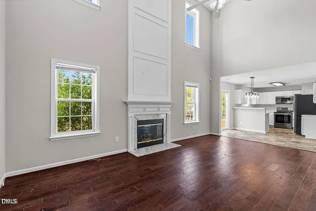 an empty room with wooden floor a fireplace and windows
