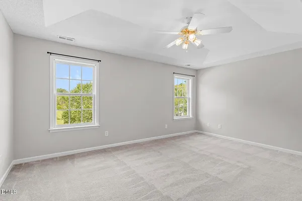 an empty room with windows and chandelier fan
