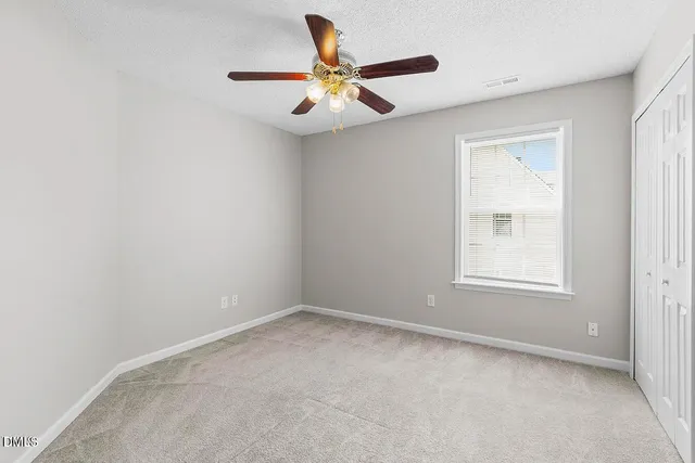 an empty room with a window and a ceiling fan
