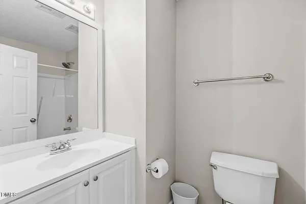 a bathroom with a toilet sink vanity and mirror