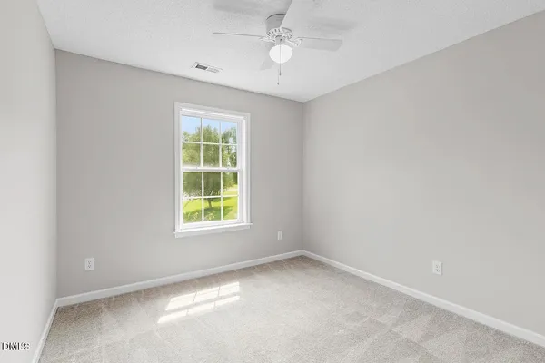 an empty room with a window and ceiling fan