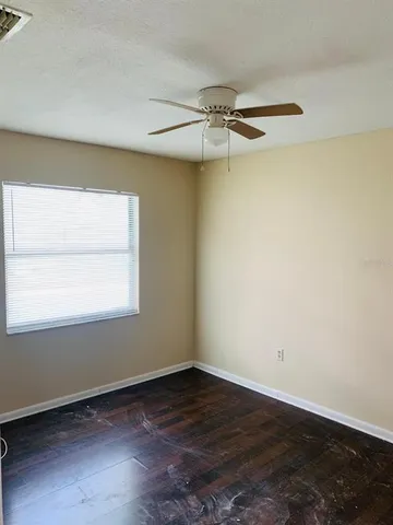 an empty room with a window and a ceiling fan