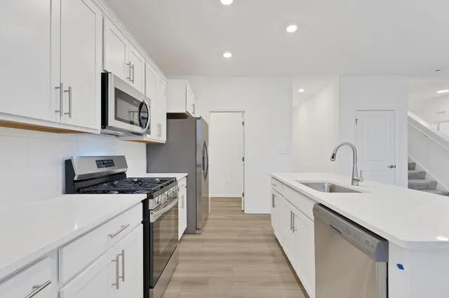 a kitchen with stainless steel appliances a sink stove refrigerator and cabinets