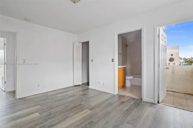 an empty room with wooden floor and a bathroom