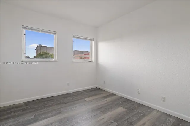 a view of a room that has wooden floor and window