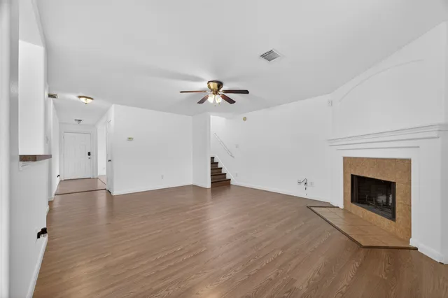 a view of an empty room with wooden floor and a fireplace