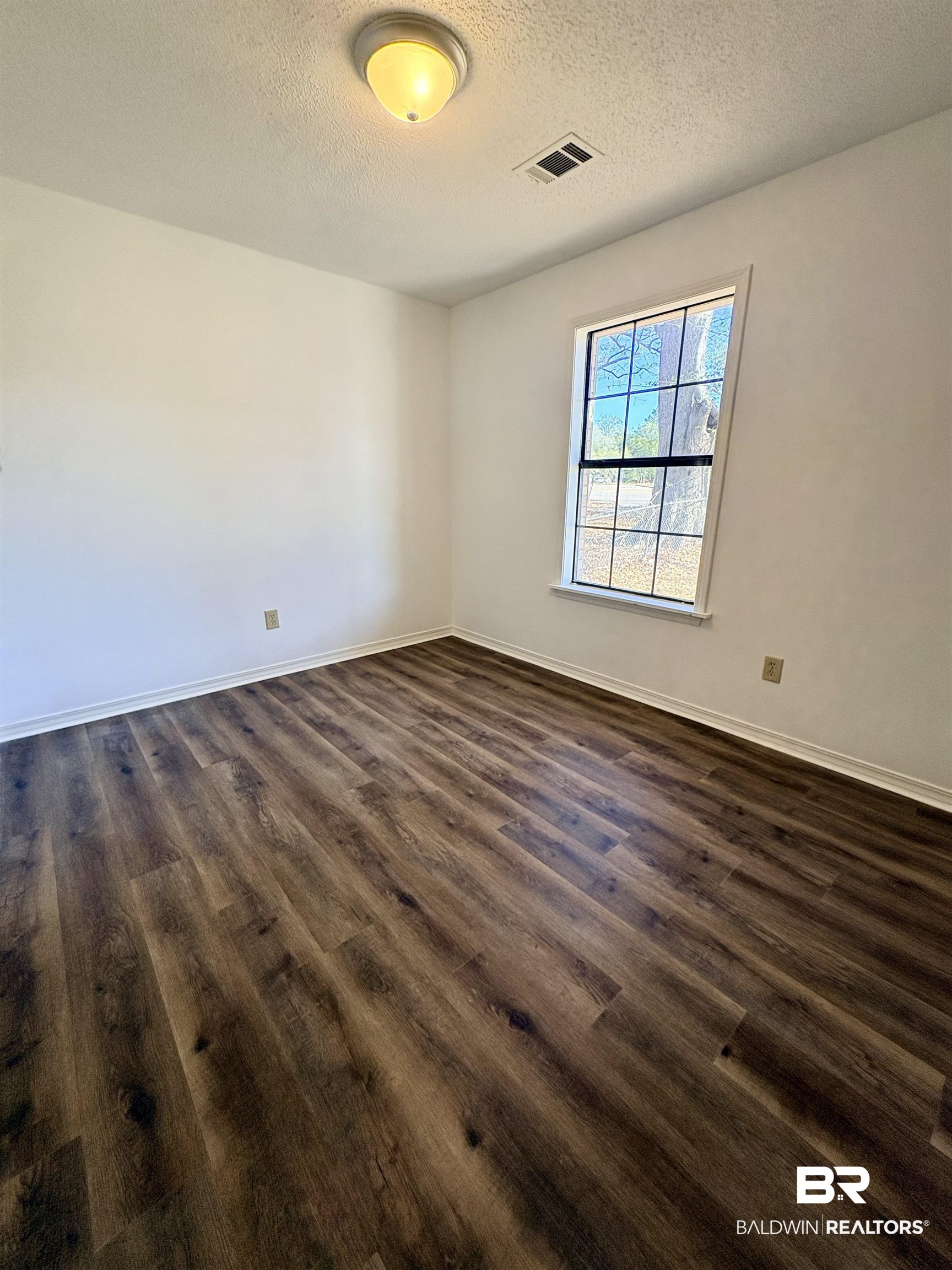 47 Fairview Street Evergreen, AL 36401 - Photo 6 of 15 Unfurnished room with a textured ceiling and dark wood-type flooring