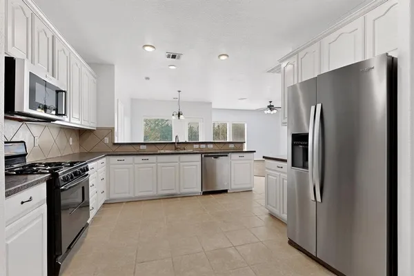 a kitchen with granite countertop white cabinets and stainless steel appliances