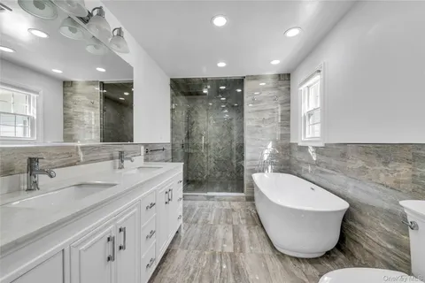 a bathroom with a double vanity sink a mirror and a bathtub
