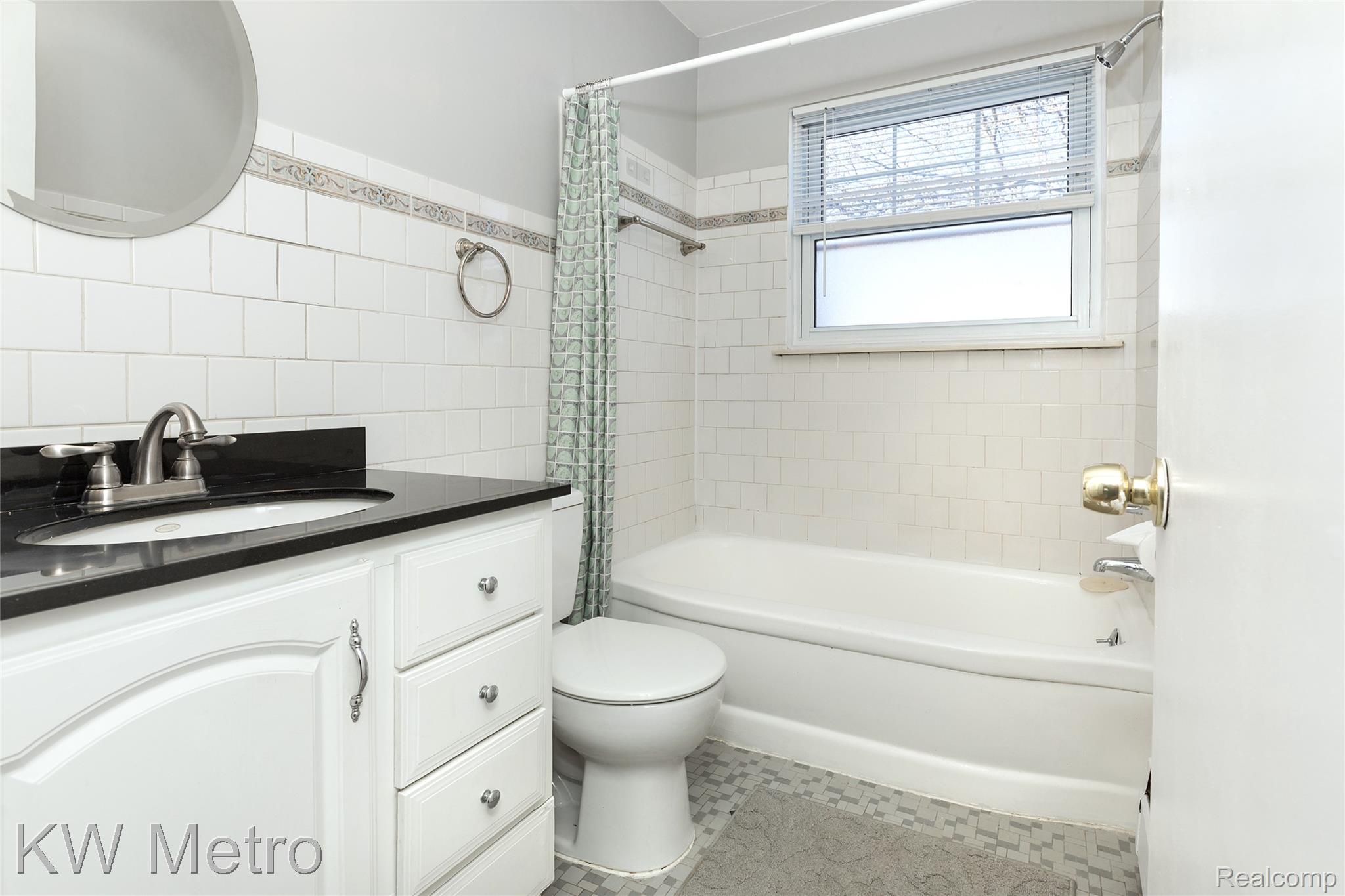 2817 West 13 Mile Road Royal Oak, MI 48073 - Photo 17 of 21 Bathroom featuring vanity, shower / bathtub combination with curtain, and tile walls