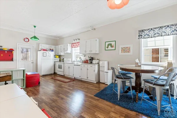 a kitchen with granite countertop a table chairs wooden floors and a view of living room