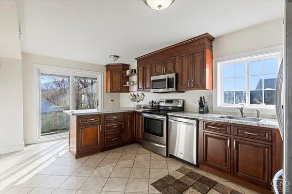 a kitchen with stainless steel appliances granite countertop a stove top oven a sink dishwasher a dining table and chairs with wooden floor