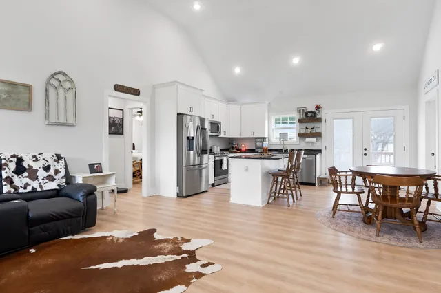 a living room with furniture and kitchen view with wooden floor