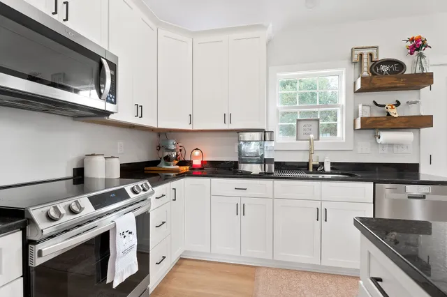 a kitchen with granite countertop white cabinets and white appliances