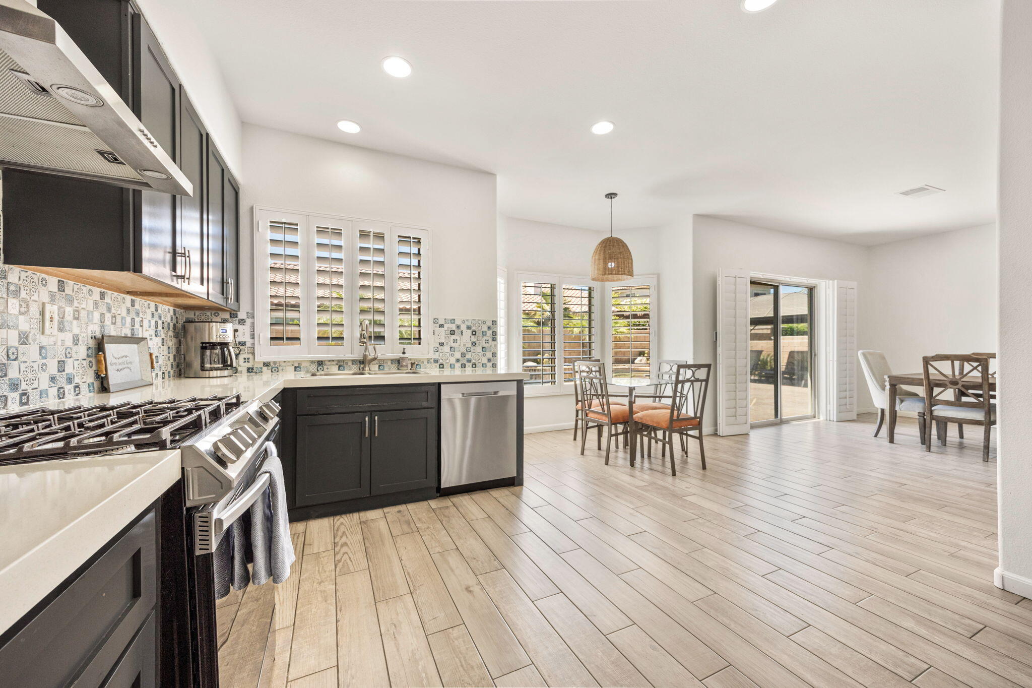 48701 Gibraltar Street Indio, CA 92201 - Photo 4 of 52 a kitchen with stainless steel appliances granite countertop a stove top oven a sink a dining table and chairs with wooden floor