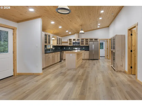 a open kitchen with kitchen island a stove a refrigerator a sink dishwasher and a oven with wooden floor