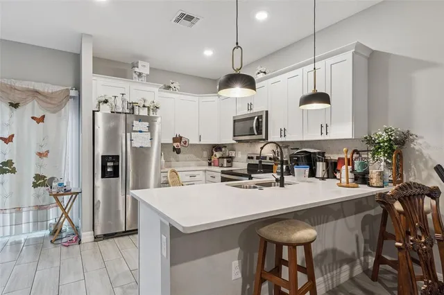 a kitchen with stainless steel appliances a table chairs refrigerator and microwave