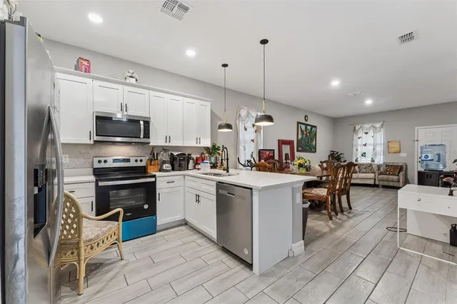 a kitchen with stainless steel appliances a stove a sink a oven a dining table and chairs
