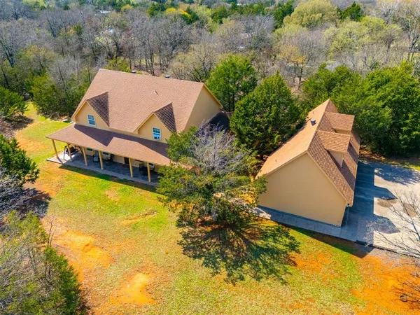 an aerial view of a house with swimming pool and large trees