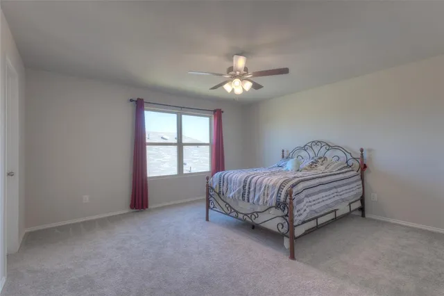 a spacious bedroom with a bed and a ceiling fan