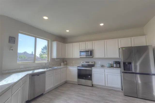 a kitchen with kitchen island white cabinets white stainless steel appliances and window